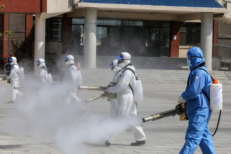 Frivillige sprøjter med desinficerende middel forud for åbningen af en  skole i Weifang i Kinas østlige Shandong provins.  Foto: Str/Ritzau Scanpix