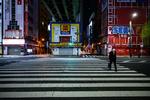 En med mand krydser gaden i området Akihabara i Tokyo. Landets sundhedsvæsen er så presset, at akutafdelinger er begyndt at afvise patienter. Foto: Philip Fong/Ritzau Scanpix
