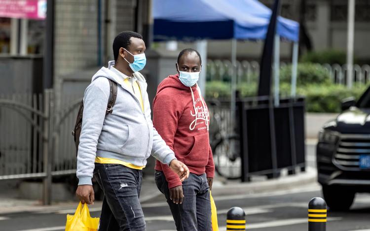  To mænd af afrikansk  afstamning krydser gaden i den kinesiske by Guangzhou. Disse to personer har  intet med den aktuelle sag at gøre.  Foto: Alex Plavevski/Ritzau Scanpix