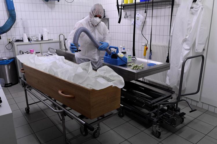  En ansat hos bedemandsfirmaet Chaudoir funeral house bærer beskyttelsesudstyr mens han gør en kiste klar til et offer for Covid-19. Foto: John Thys/Ritzau Scanpix