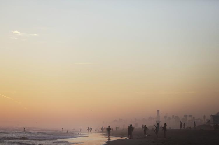 Folk går på Huntington Beach i Californien. Landet er hårdt ramt af coronavirus, og en økonomisk hjælpepakke skal afbøde dybden af krisen.  Foto: Mario Tama/Ritzau Scanpix