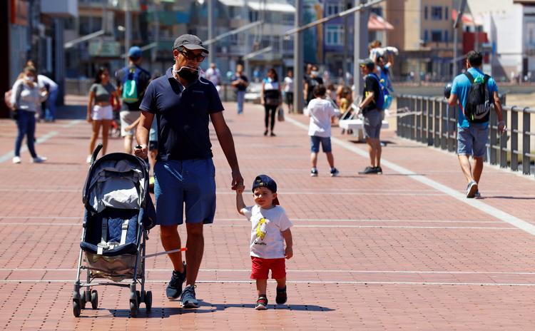 Forældre er ude og gå med deres børn ved Las Canteras beach på Gran Canaria, efter myndighederne har lempet restriktionerne for spanierne. Landet har været et af de hårdest ramte af coronavirus i Europa.  Foto: borja suarez/Ritzau Scanpix