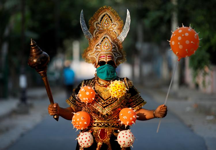Flere steder i Indien kan man se advarsler mod covid-19. På billedet er en mand klædt ud som Yama - den hinduistiske dødsgud - med forskellige covid-19 balloner for at advare befolkningen i New Delhi. Foto: Adnan Abidi/Ritzau Scanpix