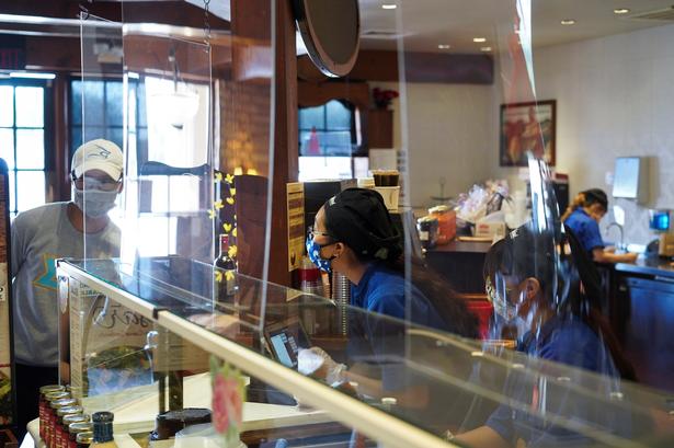 Hvordan kommer det til at se ud, når restauranterne får lov til at genåbne? Det kan man få en ide om ved at kigge mod udlandet. I Houston, Texas er man eksempelvis så småt begyndt at genstarte servicebranchen. Her på spisestedet La Madeleine bærer de ansatte mundbind, og man har hængt plastikskærme op ved disken, ligesom man har set det i supermarkeder herhjemme. 
 Foto: Go Nakamura/Ritzau Scanpix