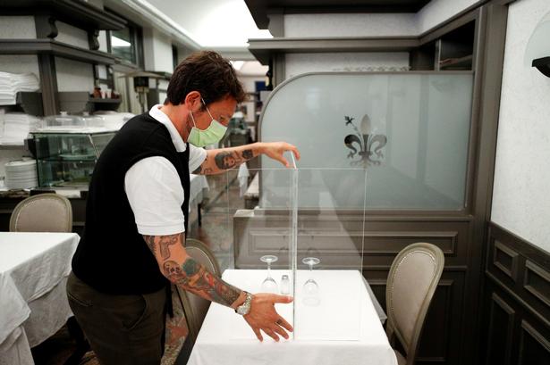 Hvordan kommer det til at se ud, når restauranterne får lov til at genåbne? Det kan man få en ide om ved at kigge mod udlandet. Her opstilles plexiglas mellem gæsterne på restauranten Nuova Fiorentina i Rom i april. Foto: Guglielmo Mangiapane/Ritzau Scanpix