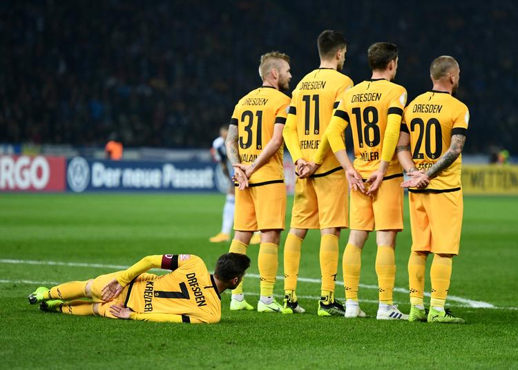 Dynamo Dresden - her i en vovet muropstilling ved et frispark i en pokalkamp tidligere på sæsonen - er sendt i karantæne på grund af to spillere med corona.  Foto: Annegret Hilse/Ritzau Scanpix
