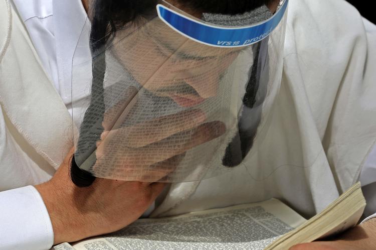 En ultraortodoks jødisk mand bærer værnemidler, mens han studerer den jødiske bibel. i Jerusalem.   Foto: Menahem Kahana/Ritzau Scanpix