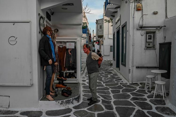 En ældre mand står i en lille by på den græske ø Mykonos. i begyndelsen af turistsæsonen.     Foto: Aris Messinis/Ritzau Scanpix