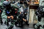 Politiet tilbageholder en kvinde i det centrale Hongkong, der er genstand for nye uroligheder. Det skyldes en ny kinesisk lovpakke, der anses for at være et nyt angreb på ytringsfriheden. Foto: Isaac Lawrence/Ritzau Scanpix
