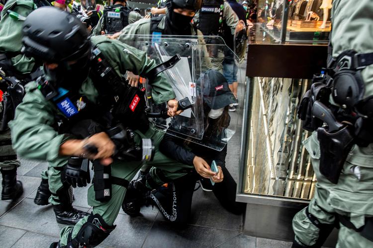 Politiet tilbageholder en kvinde i det centrale Hongkong, der er genstand for nye uroligheder. Det skyldes en ny kinesisk lovpakke, der anses for at være et nyt angreb på ytringsfriheden. Foto: Isaac Lawrence/Ritzau Scanpix