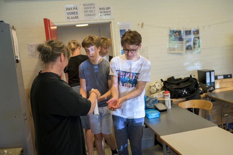 Marianne Vissing hjælper alle elever med at å sprittet hænderne af, inden de går ind til timen. Foto: Janus Engel/photographer