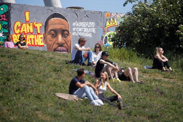 I Mauer Park i Berlin sidder folk foran et portræt af George Floyd, som døde i forbindelse med en anholdelse i USA i sidste uge.  Foto: Odd Andersen/Ritzau Scanpix