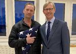Michael White (venstre), der holder et foldet amerikansk flag, står sammen med  den højtstående amerikanske embedsmand Brian Hook i Züirich Lufthavn.  Foto: -/Ritzau Scanpix