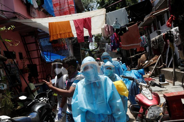 Sundhedspersonale bevæger sig gennem en smal gade i slumkvarteret Dharavi i Mumbai, Indien. På verdensplan er over 400.000 er døde med coronavirus. Foto: Francis Mascarenhas/Ritzau Scanpix