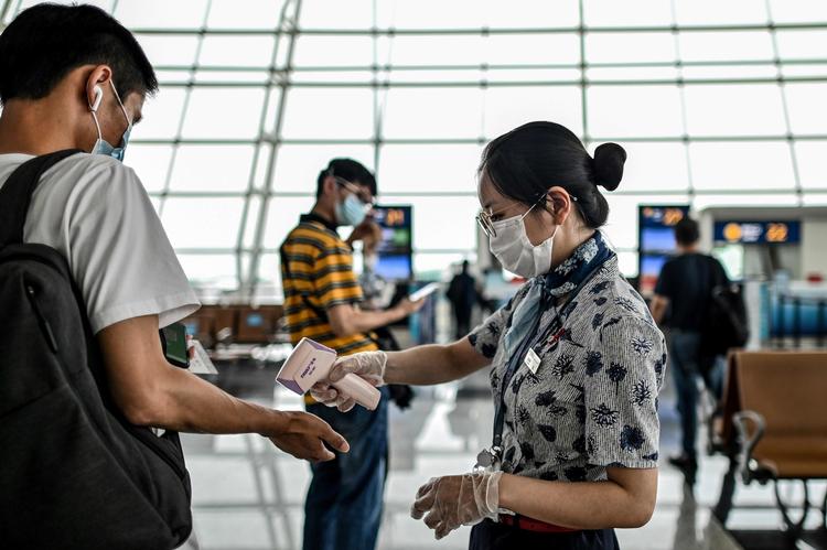 En lufthavnsmedarbejder tjekker temperaturen på en rejsende i boardingområdet i Tianhe Lufthavn i Wuhan. Landet advarer nu rejsende at tage til Australien. Foto: Hector Retamal/Ritzau Scanpix