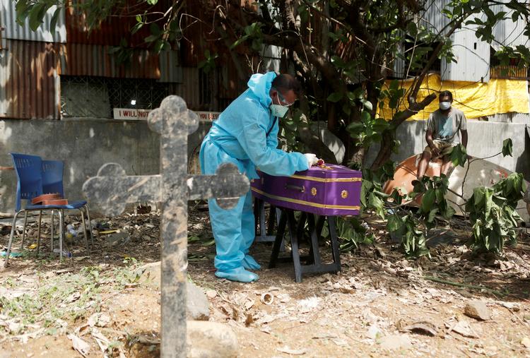 En sundhedsansat iført beskyttelsesdragt lukker på en gravplads i Mumbai låget på en kiste med endnu et offer for det voldsomme coronaudbrud i byen.   Foto: Francis Mascarenhas/Ritzau Scanpix