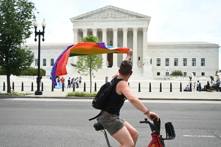  En mand vifter med regnbueflaget, mens han cykler forbi USA's højesteret. Foto: Jim Watson/Ritzau Scanpix