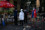 En kvinde, der bærer mundbind, passerer en sikkerhedsvagt, der tjekker folks temperatur ved indgangen til et beboelsesområde i Beijing. Byen har haft en opblussen af coronavirus. Forskere mener, det er medbragt fra Europa.  Foto: Wang Zhao/Ritzau Scanpix