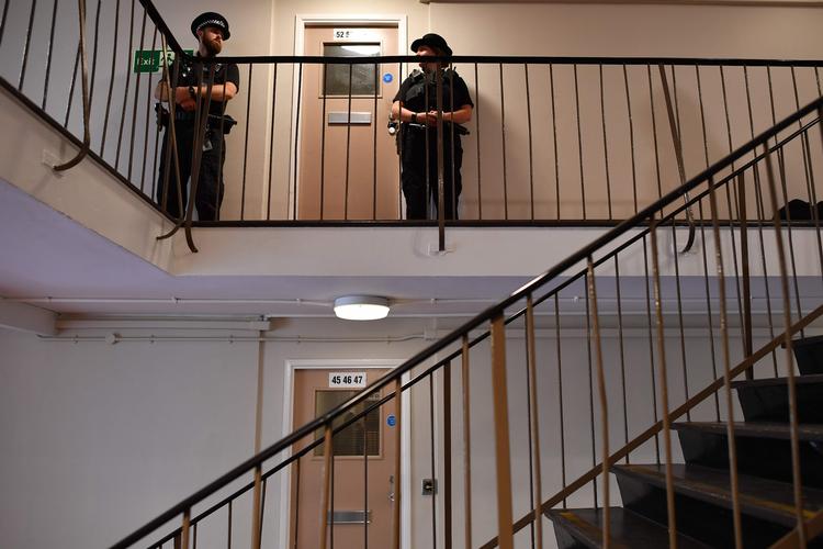 Betjente bevogter indgangen til den mistænktes bolig. Foto: Ben Stansall/Ritzau Scanpix