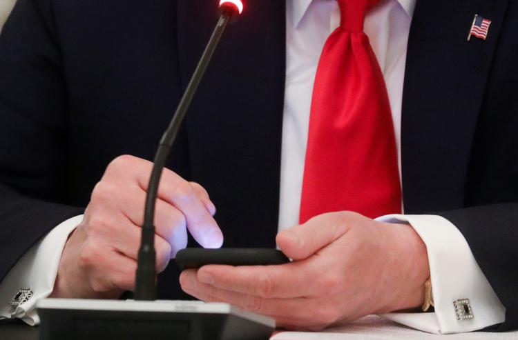   Den amerikanske præsident skriver på sin telefon under en forhandling om genåbning af små virksomheder. Lidt senere dukkede et tweet op fra hans profil.  Foto: Leah Millis/Ritzau Scanpix