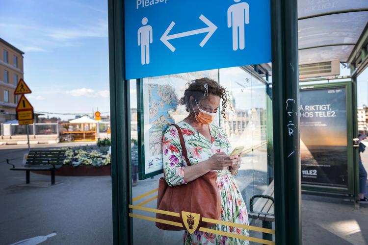 En kvinde venter på bussen i Stockholm, som har været hårdt ramt af coronavirussen.  Foto: Tt News Agency/Ritzau Scanpix