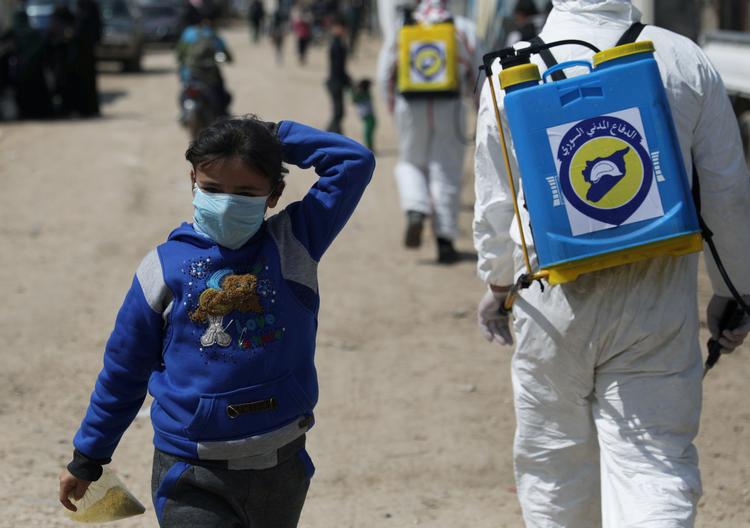 En syrisk pige bærer maske ens hun går i lejren, Bab Al-Nour. Fødevaresituationen i Syrien er forværret ifølge FN's kontor for koordinering af humanitær hjælp i Syrien, og flere sulter og lider nød.  Foto: Khalil Ashawi/Ritzau Scanpix