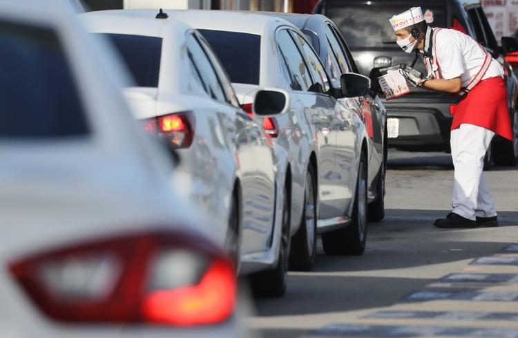 Ansatte i en 'drive-through' på en burgerbar i Californien deler mad ud iført masker. Foto: Mario Tama/Ritzau Scanpix