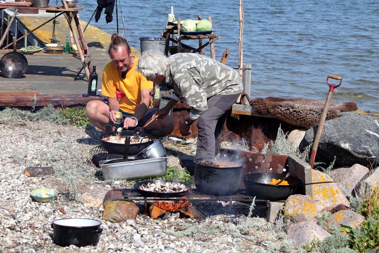 Nikolaj Kirk og Jørgen Skouboe nakker en af Endelaves 15.000 kaniner og tilbereder den i vandkanten.  Foto: Anders Roholt