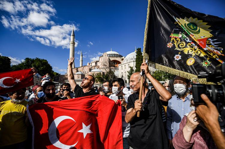 Folk fejrer foran Hagia Sofia, efter at den ændrede status igen til en moské. Det er en sejr og generobring for flere af især AKP's vælgere. Til højre ses et osmannisk våbenskjold. Foto: Ozan Kose/Ritzau Scanpix