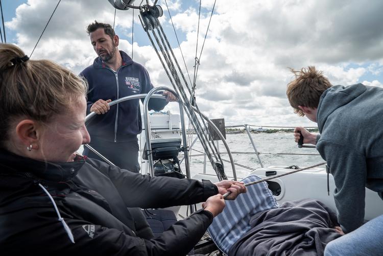 Selv med en person til at trække i tovværket og en anden ved spilhåndtaget skal der kræfter til at trimme forsejlet på vej ud af Hornbæk havn.  Foto: Ditte Lindblad/POLFOTO