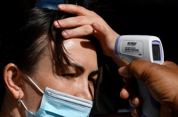 En kvinde får taget sin temperatur før et besøg på  Madame Tussauds voksmuseum i  London 1. august, hvor museet genåbnede efter længere tids nedlukning på grund af coronaepidemien. Verdenssundhedsorganisationen (WHO) vurderer, at coronapandemien bliver langvarig.   Foto: Toby Melville/Ritzau Scanpix