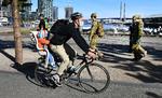 En cyklist passerer soldater i Melbourne. Storbyen indfører udgangsforbud, der skal gælde om aftenen og natten de næste seks uger. Det sker, fordi antallet af smittede med covid-19 er stigende.   Foto: William West/Ritzau Scanpix