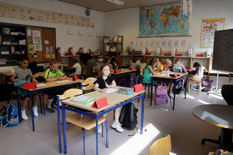 Liva Maria Rye Færch Nielsen (forrewst) og hendes klassekammerater i 2.b. er tilbage i klasselokalet på Skovlunde Skole. Liva er glad for, at legepladsen er tilbage som før: »Det var irriterende, når man ikke kunne komme til rutsjebanen. Men nu må vi være over det hele«. Foto: Jesper Houborg/POLFOTO