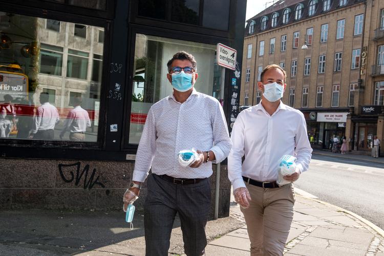 Fra mandag blev det et krav at bære mundbind i den offentlige transport i Aarhus, og Jacob Bundsgaard (th) gik sammen med rådmand Bünyamin Simsek på gaden for at dele mundbind ud til buspassagerne.   Foto: Marie Ravn/Marie Ravn