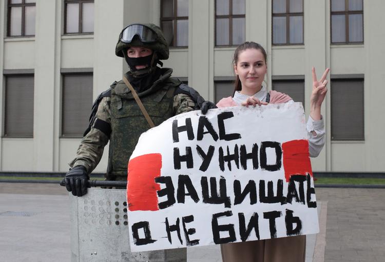 En kvinde bærer et skilt ved siden af en hviderussisk soldat. Efter landets masseanholdelser og hårde kurs mod demonstranter enes EU's udenrigsministre om sanktioner. Foto: Siarhei Leskiec/Ritzau Scanpix