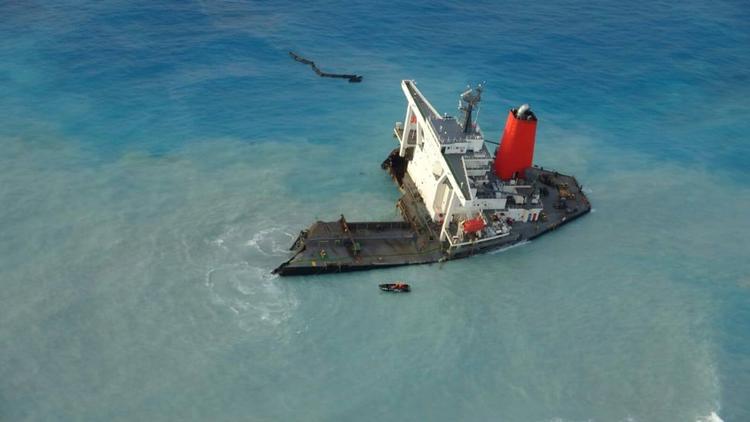 Den ene del af det japanske skib, MV Wakashio, ses her fra sattelitbilleder. Søndag brækkede skibet over i to dele, og nu har myndigheder indledt arbejdet med at bugsere den største del - forstævnen - ud på havet, hvor den skal sænkes. Men den beslutning møder kritik.  Foto: Mobilisation Nationale Wakashio/Ritzau Scanpix