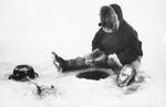 Man mener, at ordet eskimo etymologisk set betyder 'den der spiser råt kød'.  Her er det en grønlandsk fanger, der venter på fisk, mens han nyder en pibe tobak.  Foto: Polfoto/POLFOTO