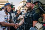 En højreorienteret trykker hånd med en Black Lives Matter-demonstrant i Louisville, Kentucky. Selv om der har været voldsomme optøjer, er mere end 93 procent af BLM-demonstrationer i USA er foregået uden alvorlige skader, viser ny rapport. Foto: Brandon Bell/Ritzau Scanpix
