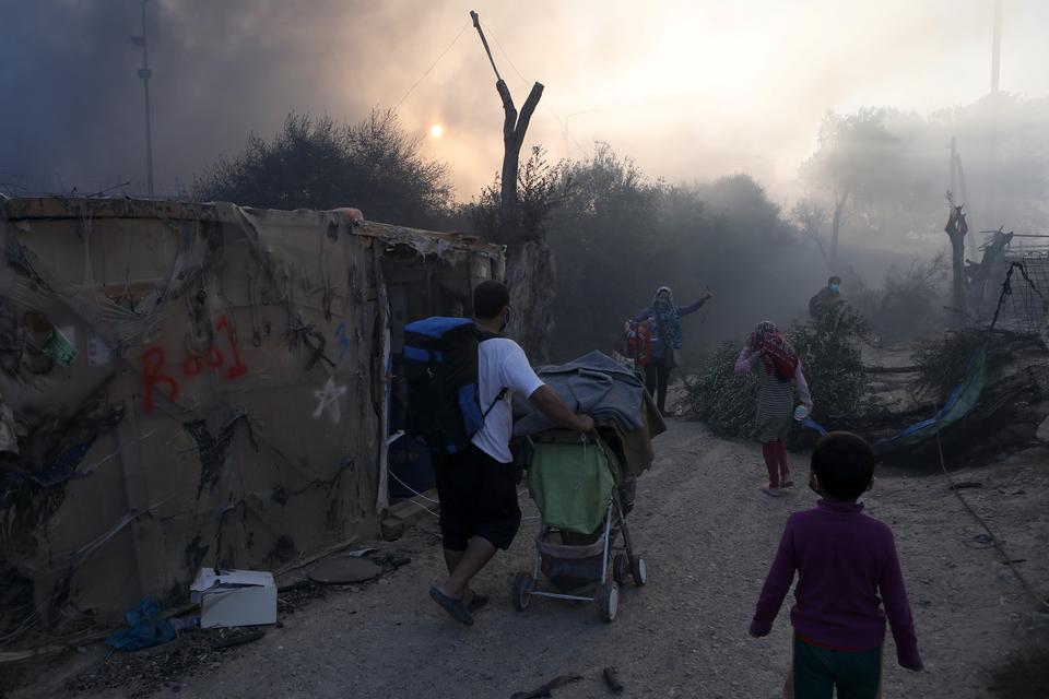 Beboere forlader lejren med deres ejendele efter branden. Foto: Elias Marcou/Ritzau Scanpix