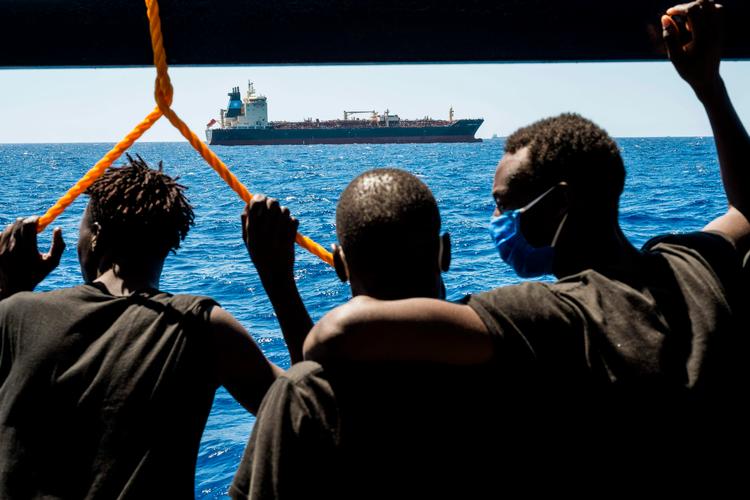 Migranter om bord på redningsskibet ser på olietankeren Maersk Etienne ud for Maltas kyst. Mærsk-skibet har huset 27 migranter i mere end en måned, fordi ingen europæiske lande ville tage i mod dem.   Foto: Thomas Lohnes/Ritzau Scanpix