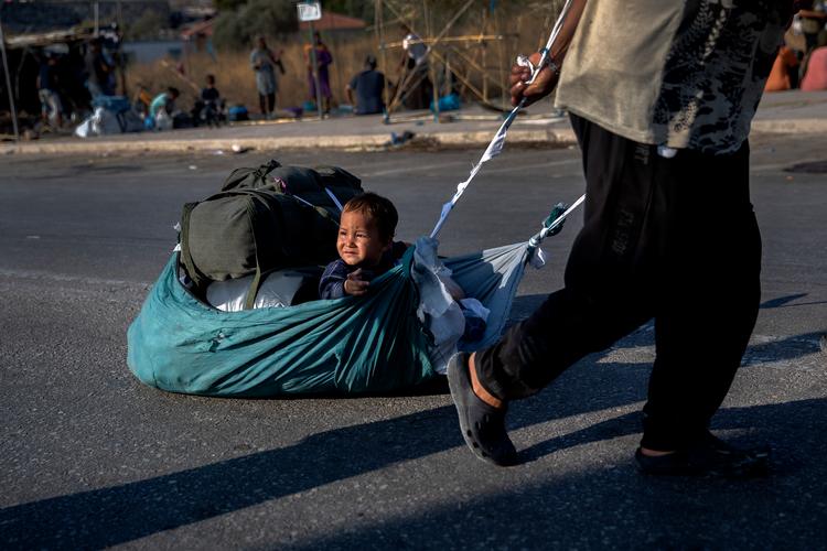 Endnu en familie har kurs mod politiets afspærring og indgangen til den nye lejr på Lesbos. Junior fik lov at hvile fødderne.
 Foto: Jacob Ehrbahn/POLFOTO