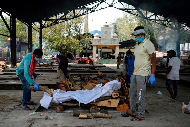 Pårørernede i New Belhi, Indien, gør klar til at brænde en person, der er død og smittet med coronavirus. Indien er et af de lande i verden med flest døde med corona i kroppen. Billedet er fra juni i år.  Foto: Sajjad Hussain/Ritzau Scanpix