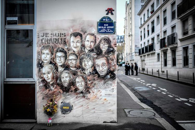   Det første terrorangreb på Charlie Hebdo i 2015 kostede 12 mennesker livet. De er portrætteret af den franske kunstner Christian Guemy på billedet her, som politifolk kigger på.
 Foto: Stephane De Sakutin/Ritzau Scanpix
