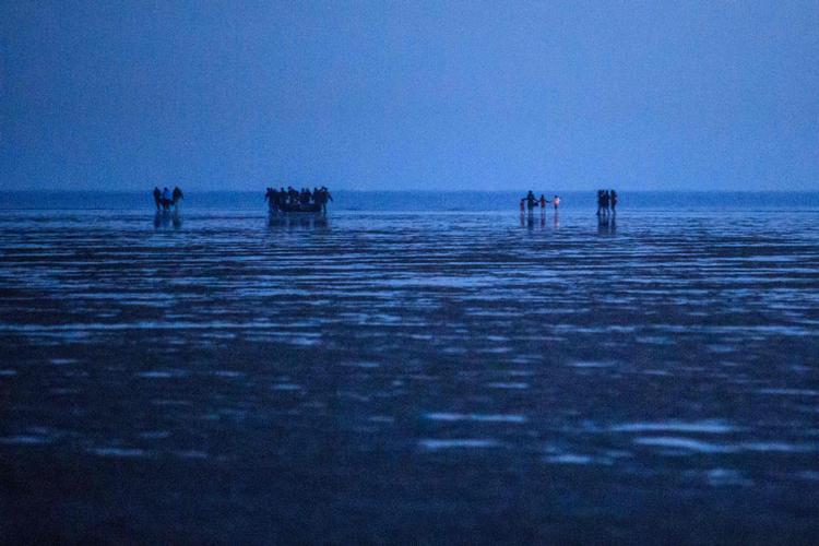 En gruppe asylansøgere bærer en båd og en moter på den franske kyst ved Dunkerque 22. september. Den britiske kyst er blot 33 kilometer væk. Foto: Sameer Al-doumy/Ritzau Scanpix
