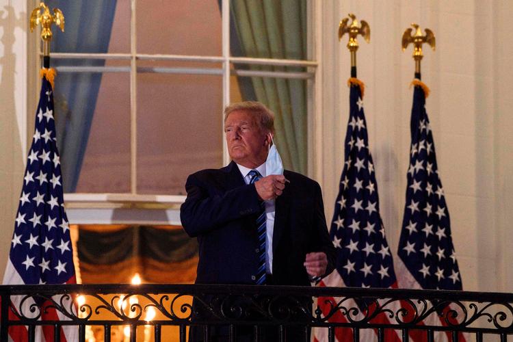 Præsident Trump hiver sin ansigtsmaske af for snurrende tv-kameraer, inden han, syg af corona, går ind til sine medarbejdere i Det Hvide Hus. Foto: Nicholas Kamm/Ritzau Scanpix