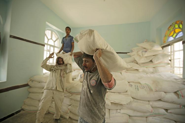 Yemenitiske mænd bærer madforsyninger leveret af FN's fødevareprogram i byen Sanaa. Foto: Hani Mohammed/Ritzau Scanpix