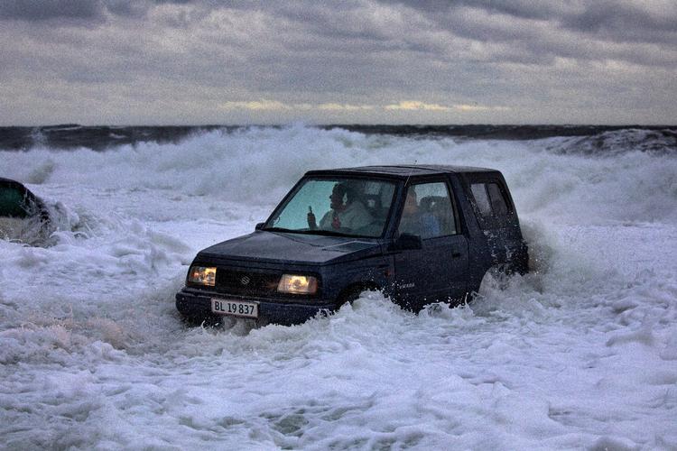 En bil bliver fanget af vandet på parkeringspladsen ved Gudhjem Røgeri.  Foto: Jacob Ehrbahn/POLFOTO