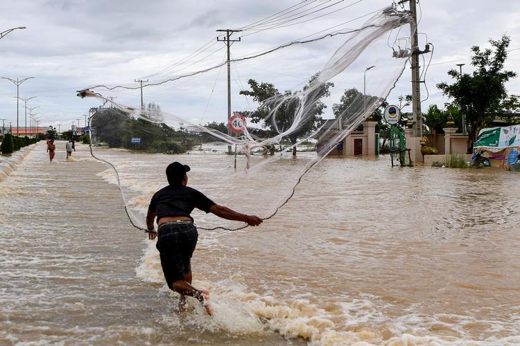 Millioner af mennesker må som manden på billedet indrette sig på en ny virkelighed på grund af klimaforandringer. Han forsøgte i sidste uge at kaste sit fiskenet ud i et oversvømmet område i Phnom Penh i Cambodia.   Foto: Tang Chhin Sothy/Ritzau Scanpix