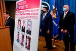 En plakat med de seks personer, der er eftersøgt for cyberangreb, blev præsenteret på et pressemøde.  Foto: Andrew Harnik/Ritzau Scanpix