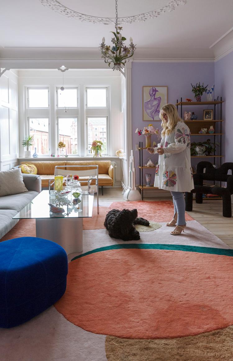 Stuen viser tydeligt, at Herle Jarlgaard Hansen elsker farver. Hun elsker også at have familie og venner på besøg, så det var vigtigt at indrette med mange siddepladser og i bløde sofaer. Glasbordet er hjemmelavet af en vintageglasplade og to skumskamler af en art. Reolen er fra Moebe, og gulvtæppet fra Layered x Poppykalas. 